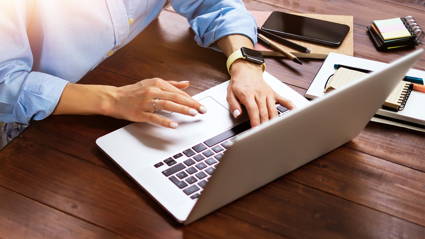 a top down shot of a woman taping on a laptop on a desk