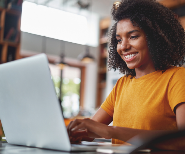 A woman smiling, working in front of a laptop