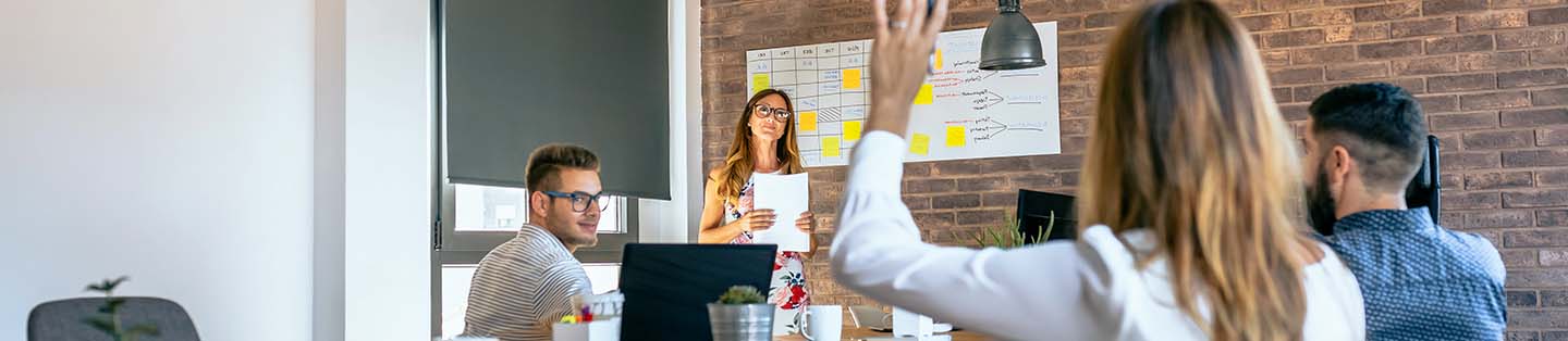 A women raising her hand to ask a question to a lecturer